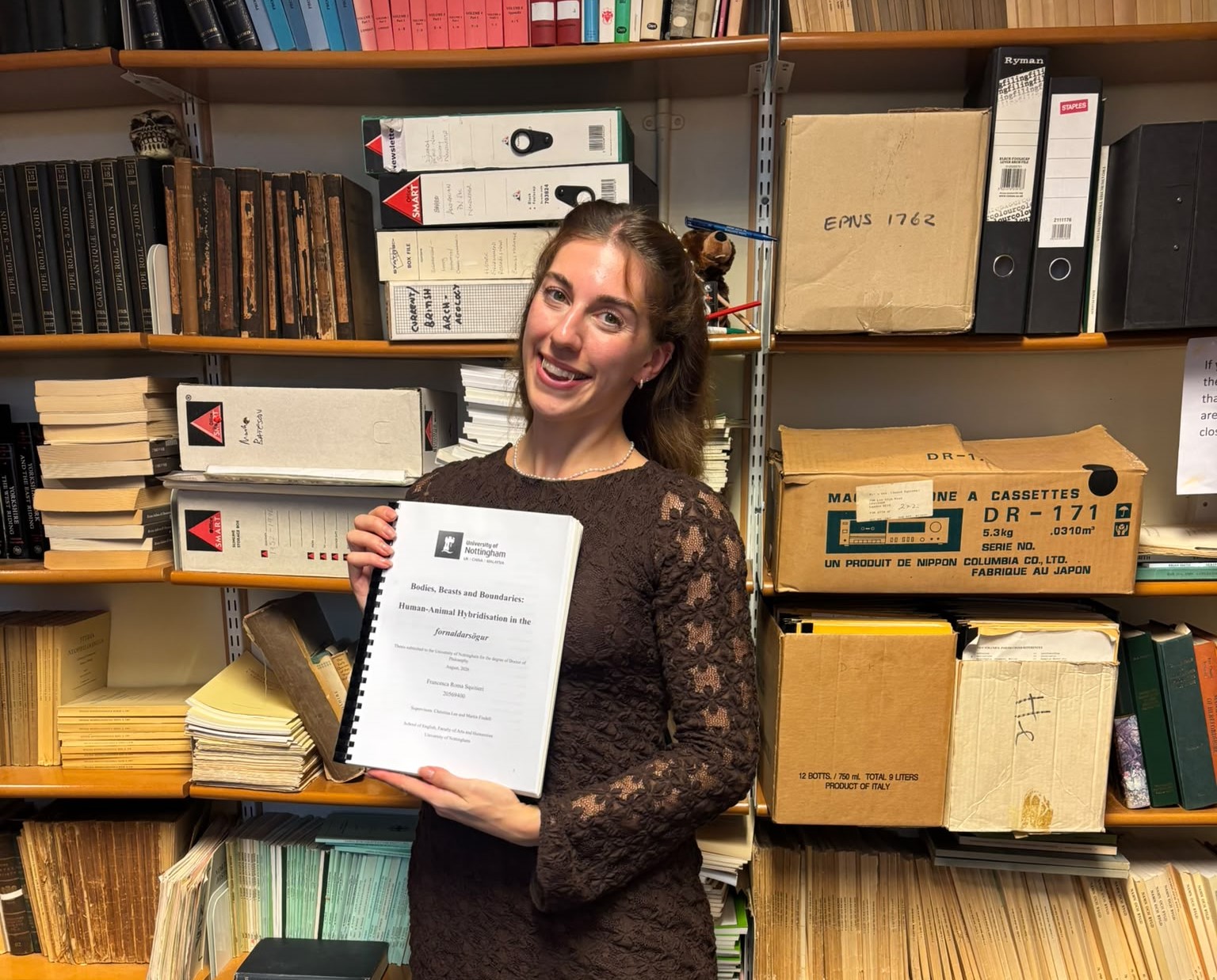 Francesca posing with her thesis in the office after her viva
